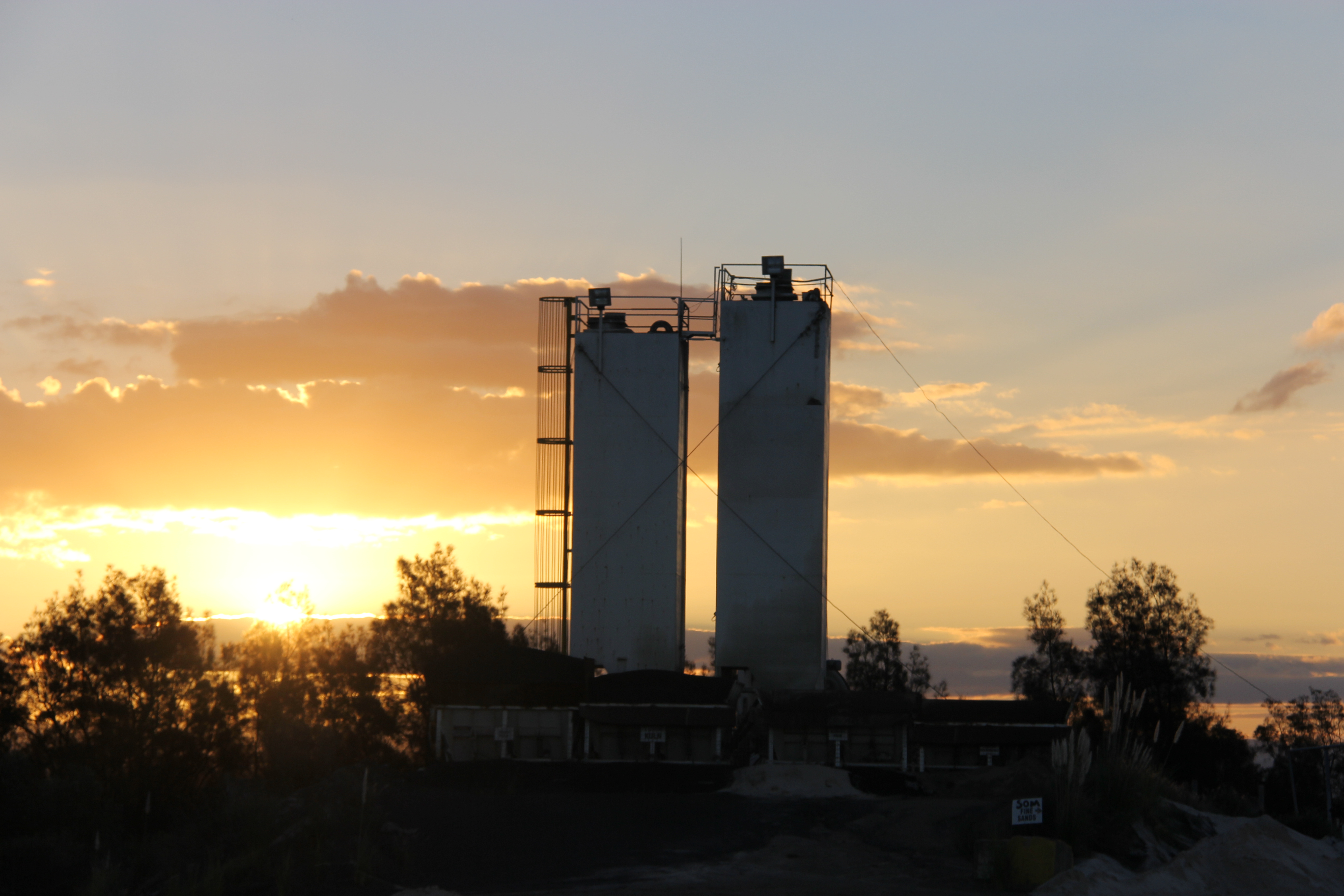 Cement plant silhouetted at sunset, representing Heidelberg Materials' public reports and transparency