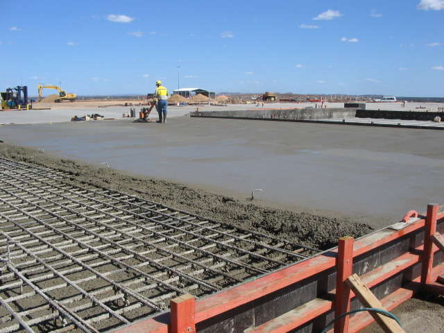 Mobile concrete plant in operation with workers and paving frame