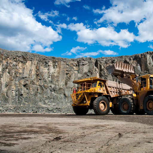 Large yellow mining truck driving through a quarry at Heidelberg Materials site under blue sky