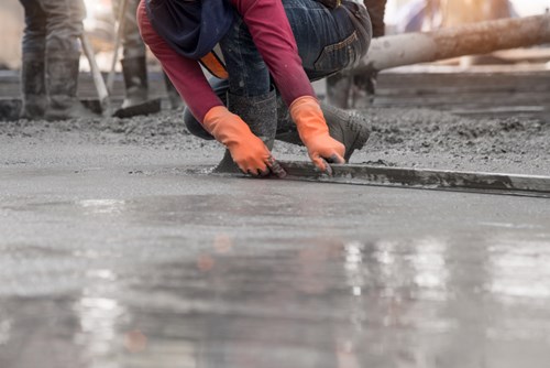 Workers finishing concrete surface inside warehouse