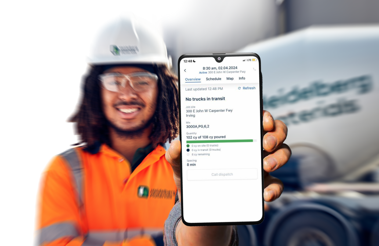 Heidelberg Materials worker in safety gear holding a mobile phone displaying the OnSite platform for order tracking and delivery updates