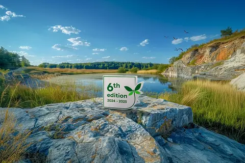 Quarry Life Award 6th edition sign on rock overlooking a rehabilitated quarry lake with greenery and blue sky