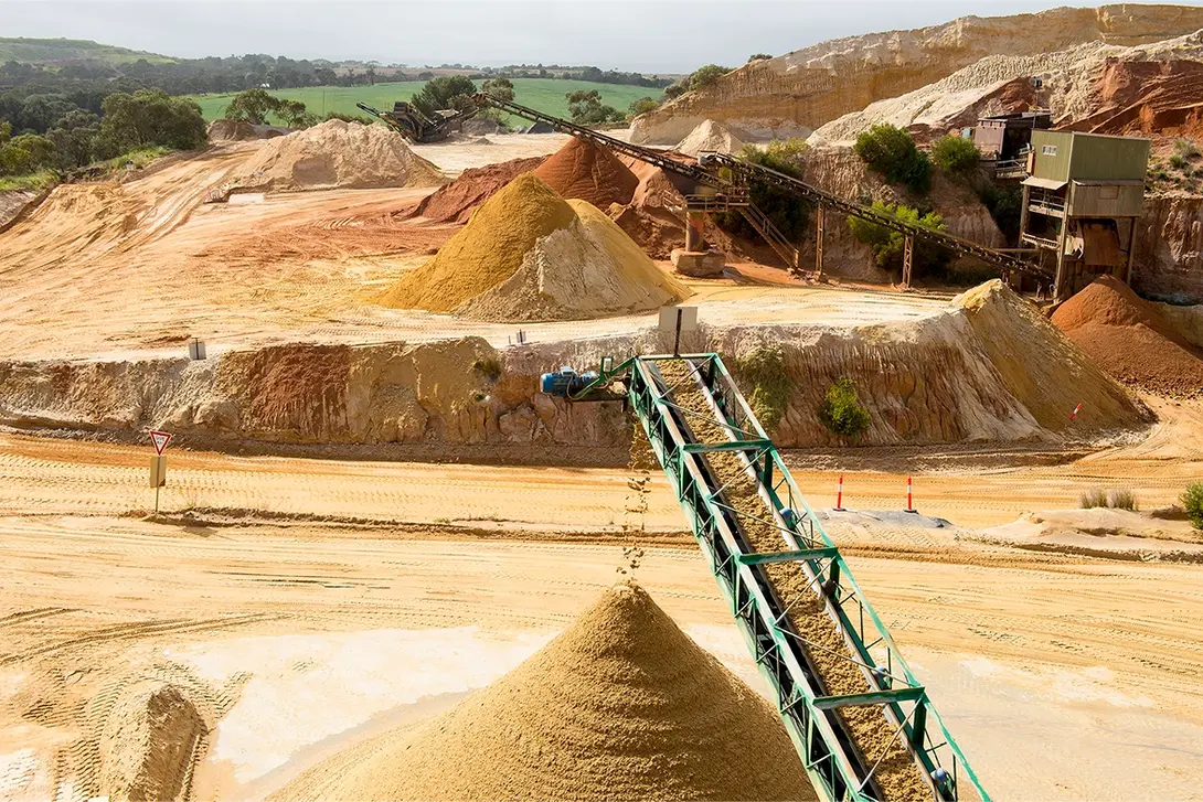 Quarry site with conveyor belts transporting sand and aggregates into stockpiles, showcasing material processing for construction and infrastructure use.