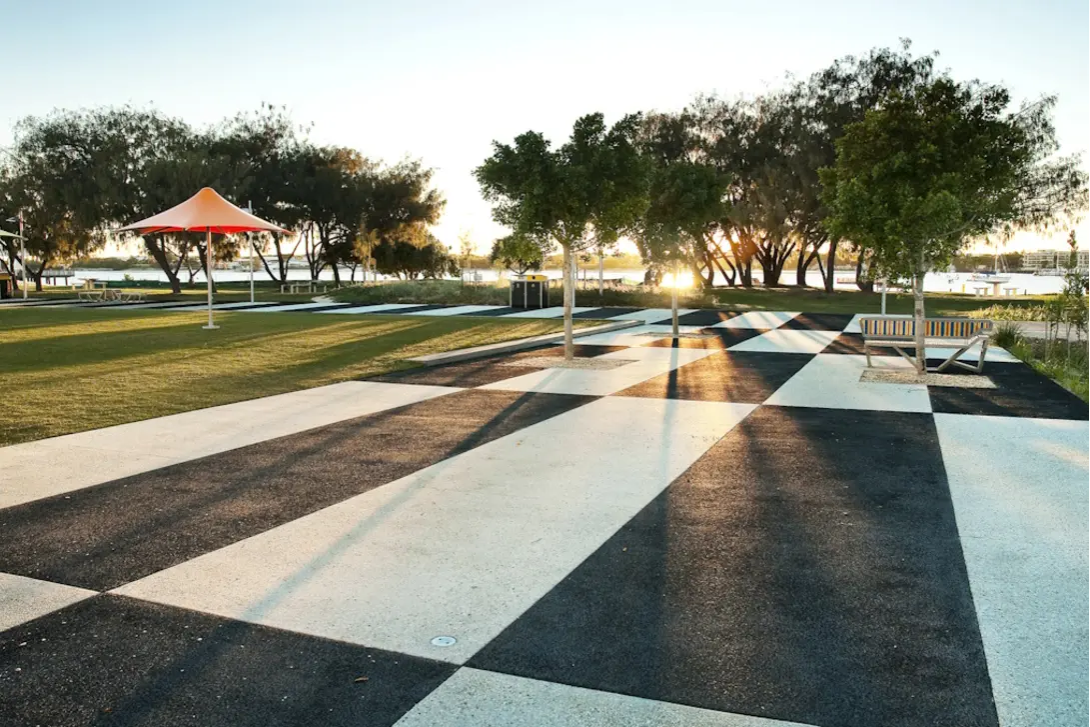 Modern landscaped park with patterned black and white Imagecrete Colour concrete paving, featuring geometric designs, seating areas and shaded outdoor spaces.