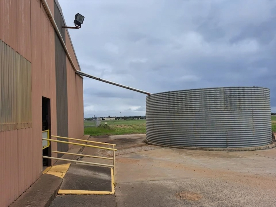 Rainwater harvesting infrastructure at the Heidelberg Materials Australia Dubbo Concrete Plant, featuring rooftop water collection piping connected to a large onsite water storage tank.