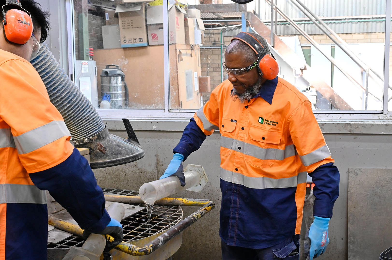 Heidelberg Materials laboratory technicians conducting technical testing and sample analysis while wearing appropriate personal protective equipment (PPE) in a quality control laboratory.