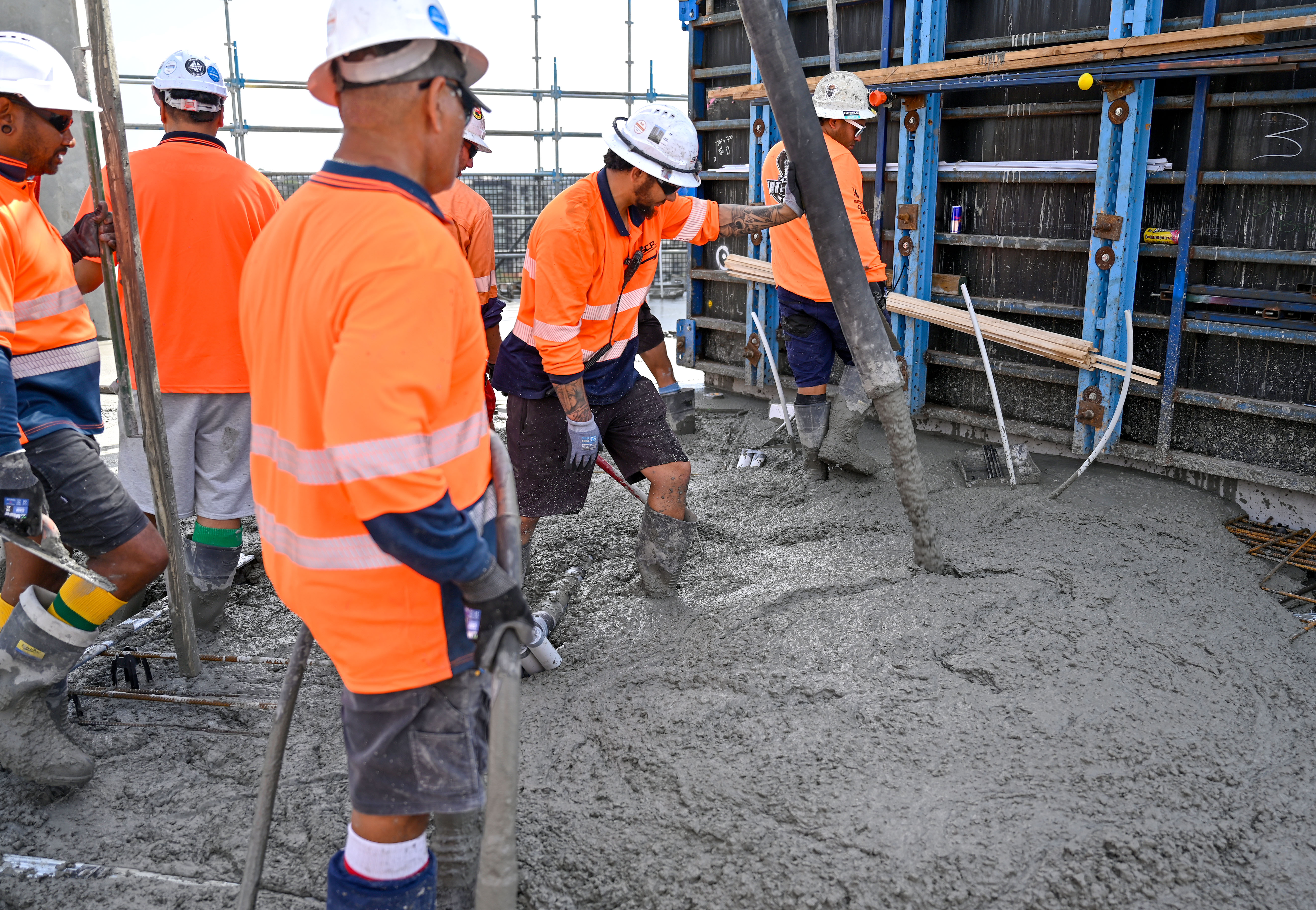 Construction crew pouring and placing ready-mix concrete into formwork at a commercial building site using a concrete pump, supplied by Heidelberg Materials Australia.